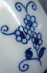 china statuette of C18 lady: closeup of blue flower on her cloak