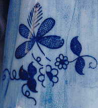 china teaparty ornament: closeup of flowers on the back of left hand lady's skirt
